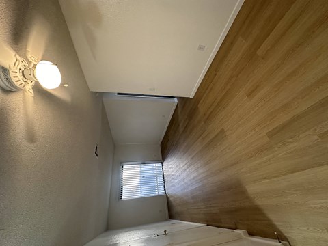 a view down a hallway with wood flooring and a window
